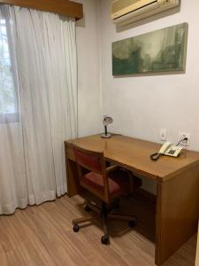 圣保罗EXECUTIVE SUITE 106a VILA OLIMPIA的一张带电话和椅子的木桌