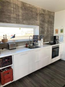 KópaskerMelar Guesthouse的厨房配有白色橱柜、水槽和窗户。