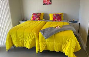 夏威夷欧申维尤The Art Garden- Hibiscus Guesthouse的一间卧室配有黄色床和黄色棉被