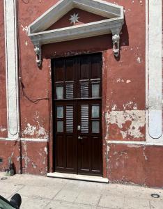梅里达Departamento Barrio de Santiago的一座红色的建筑,上面有木门