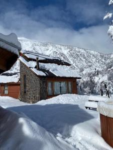 拉斯特朗卡斯奥拓科迪勒拉山林小屋的一座雪覆盖的房子,背景是一座山