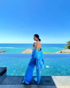 努沙杜瓦Cliff front luxury Olala Nusadua Beach的身着蓝色衣服站在海边的女人