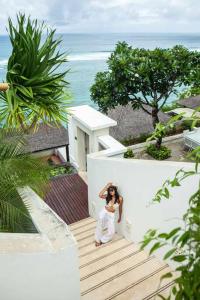 努沙杜瓦Cliff front luxury Olala Nusadua Beach的一位妇女站在离海洋不远的楼梯上