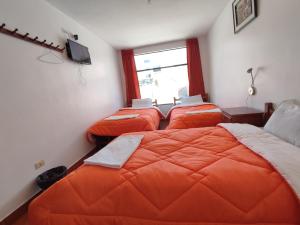 瓦拉斯Sunrise Guest House的一间卧室设有三张床、橙色床单和窗户