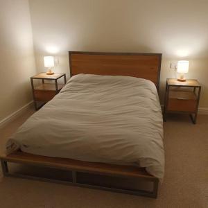 LostockChurstonBnB, private flat within family home, Bolton的一张带白色床单的床和两个带灯的床头柜