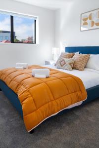 基督城The City's Best Kept Secret 2 bed 2 bath的一间卧室配有一张带橙色毯子的大床
