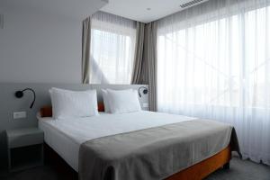 米什科尔茨Premier Hotel Miskolc的一间卧室配有一张带白色床单和窗户的床。