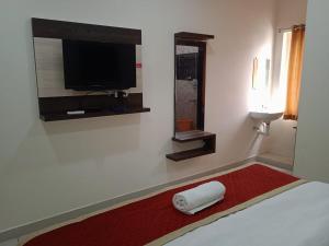 巴德拉恰拉姆SRI BHAVYARESIDENCY的一间卧室配有一张带电视的床和红色地毯。