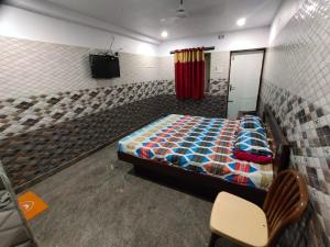 ArakkonamSri Mahalakshmi Deluxe Lodging Arakonam的一间卧室,卧室内配有一张床和一把椅子
