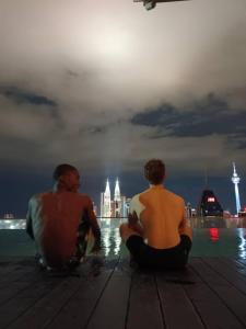 吉隆坡Regalia Exclusive Hostel的两个坐在码头上看着水面的人