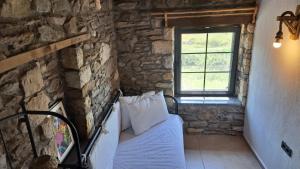 伊兹密尔Peaceful Stone House with Nature View in Karaburun的卧室配有一张石墙床