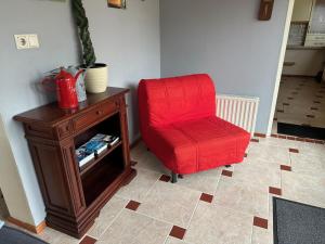 GaastVakantiehuis het Voorhuis op Landgoed koepeltjesplaats的一张红色椅子,坐在木柜旁