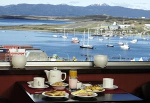 乌斯怀亚乌斯怀亚MIL810酒店的一张带食物盘的桌子,享有海港的景色