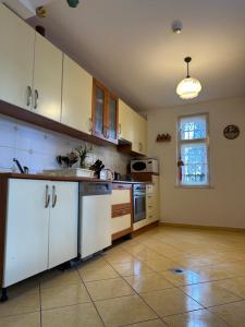 巴拉顿城堡Party Villa Holiday Rent Balatonfoldvar的厨房配有白色橱柜和瓷砖地板。
