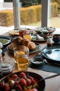 博克斯特尔Bed & Wellness Boxtel, 4 persoonskamer met eigen badkamer的餐桌,带食物盘和橙汁杯
