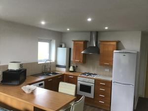 莫顿Dovedale Apartment的厨房配有木桌和白色冰箱。