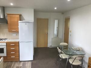 莫顿Dovedale Apartment的厨房配有白色冰箱和玻璃桌