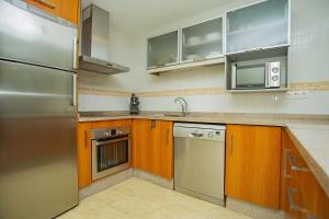 坎波阿莫242 Relax & Enjoy Alicante Holiday的厨房配有木制橱柜和不锈钢冰箱。