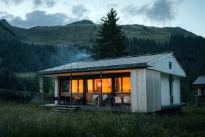 Davos WolfgangChalet Horn的田野上的一个小房子,灯亮着