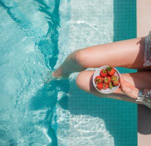 阿斯格罗Sun City Luxury Apartments的在游泳池里拿着一碗草莓的人