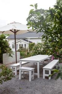 恩雪平Vallby Cottage的一张野餐桌和两张带雨伞的长凳