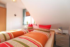 诺德代希Ferienwohnungen Wiese的卧室内的两张床,配有红色和橙色枕头