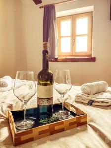 维帕瓦Boutique Rooms & Winery Žorž的床上有一瓶葡萄酒和两杯酒