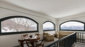 贝拉吉奥Il Larice - Agriturismo Alpe del Ville San Primo by Wonderful Italy的客房设有3扇窗户和桌椅。
