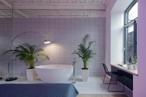 久姆里Major's House Gyumri的浴室设有白色浴缸和2种盆栽植物