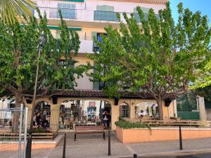 卡西斯Le Best à Cassis,Top emplacement,Parking,double balcon的前面有树木和长凳的建筑