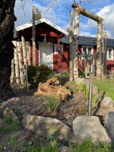 法尔肯贝里Mindre lägenhet i en lantlig miljö i Skrea的一座花园,在一座建筑前有木头和岩石