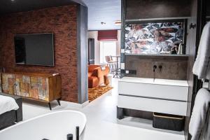 哈林亨"DE BANK" - Hotel Apartments的一间带水槽的浴室和客房内的电视