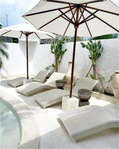 坎古Kemari Studio的一组椅子和遮阳伞,位于游泳池旁