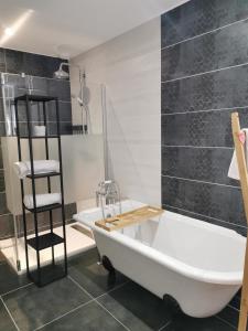 Sainte-Croix-sur-MerChambre de l'Iris的浴室设有白色浴缸和黑色瓷砖墙。