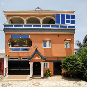 Agbata Guest House的一座橙色的建筑,设有蓝色的窗户和车库