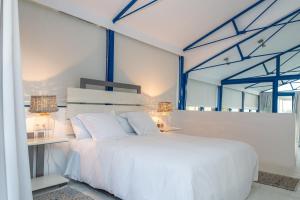维拉诺瓦德卡塞拉Lightbooking Praia Fabrica Algarve的卧室配有白色的床和桌子
