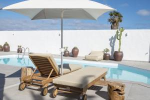 特尔德Lightbooking Edem Playa del Hombre的游泳池旁的椅子和遮阳伞