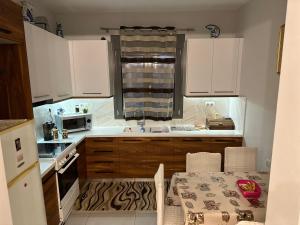 比雷埃夫斯A&A Apartment的厨房配有白色橱柜、桌子和水槽。