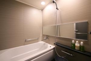东京格拉斯丽新宿酒店的浴室配有白色浴缸和镜子
