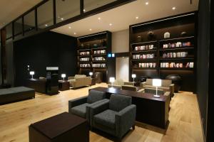 东京格拉斯丽新宿酒店的客厅配有椅子、桌子和书架