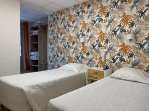勒旺Hôtel La Vigneraie的卧室内的两张床,配有花卉壁纸