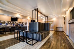 托皮卡SureStay Plus Hotel by Best Western Topeka的一间酒吧,房间中间有条纹椅子