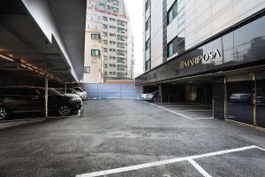 平泽市Mariposa Hotel Songtan的停车场,停车场的汽车停在大楼前