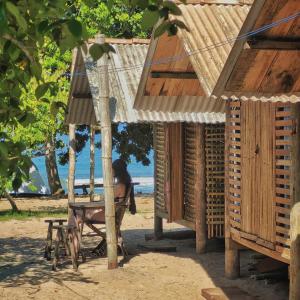 帕拉蒂Cabana Caiçara Praia do Sono Paraty RJ的坐在海滩桌子上椅子上的女人