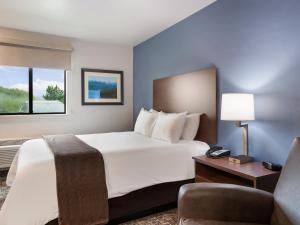 卡利斯佩尔My Place Hotel-Kalispell, MT的酒店客房带一张大床和一把椅子