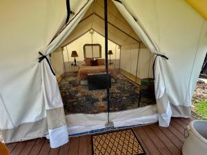 PaoniaZinnia Glamping Tent at Zenzen Gardens的帐篷内的卧室,配有一张床