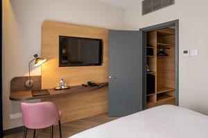布鲁塞尔布鲁塞尔格雷西姆贝尔森酒店的一间卧室配有书桌,墙上配有电视