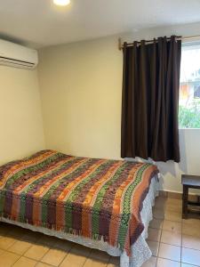 博卡德尔里奥Departamento centro de Boca del Río的一间卧室配有一张带五颜六色被子的床和一扇窗户