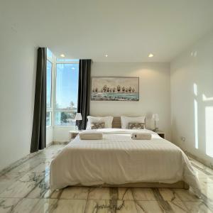 吉达Urban Luxury Apartment的白色的卧室设有一张大床和一个大窗户
