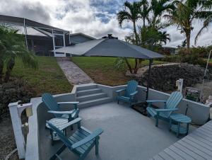珊瑚角Blue Flamingo - Pool, Sunsets, Dock, Lift, Direct Gulf Access!的庭院配有蓝色的椅子和遮阳伞。